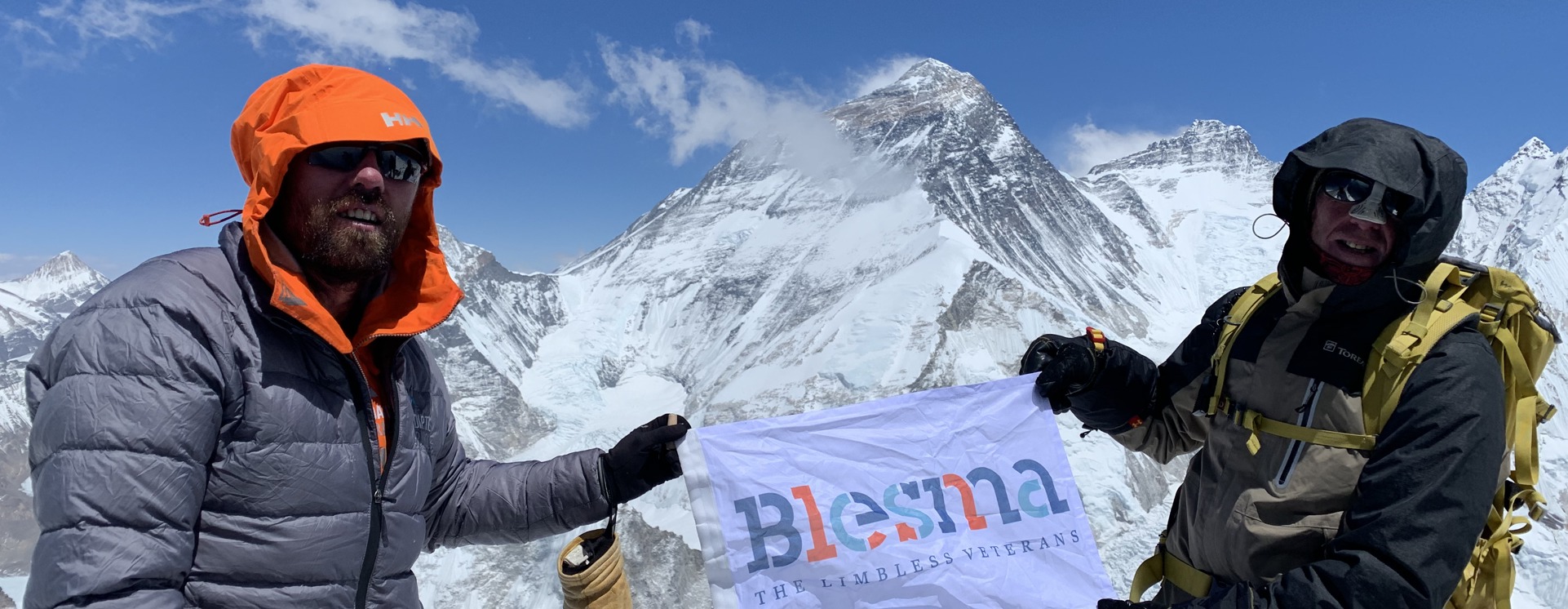 Two men stand atop everest with a Blesma Banner