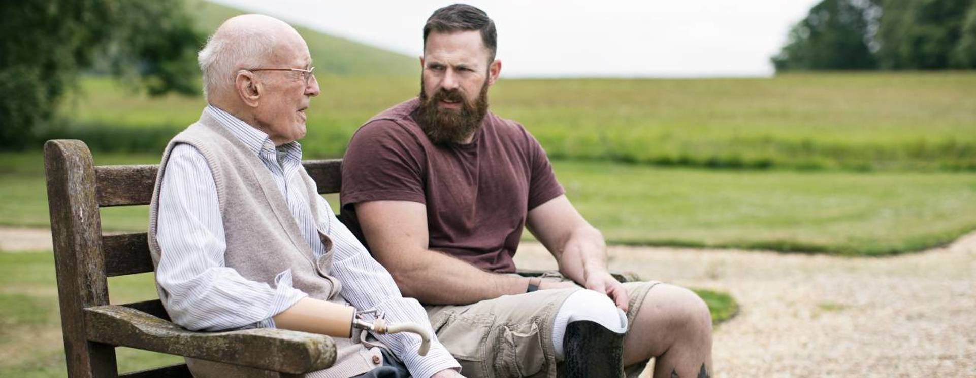 Two war veterans with prosthetic limbs sat on a bench